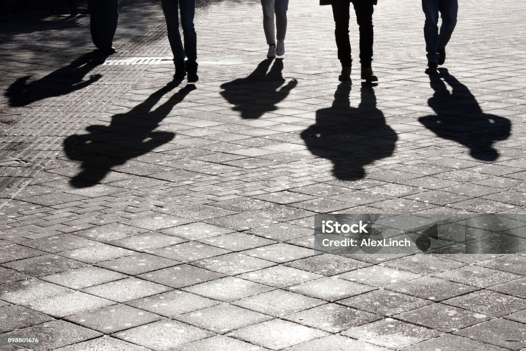 Leegs and shadow of five people Legs and shadow of five young person approaching on city street pedestrian sidewalk Shadow Stock Photo