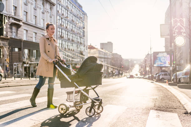 istock Mother pushing baby stroller on lined pedestrian crossing 898803010