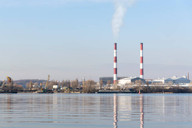 istock Two smoking chimneys on the river bank 898805432