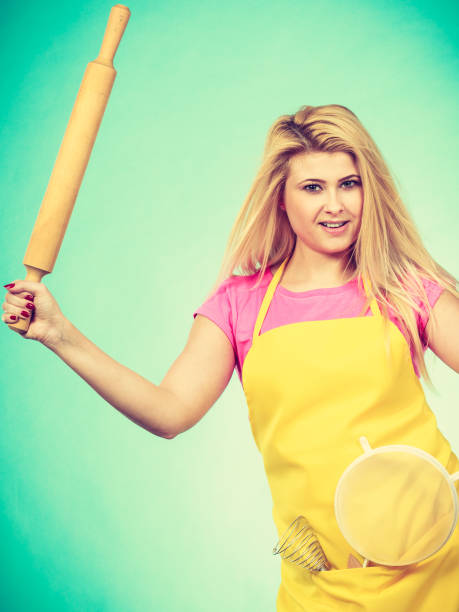 istock Woman wearing apron holding colander and rolling pin 898812492