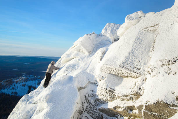 der bergsteiger den gipfel klettern bedeckt mit eis und schnee, mann wanderer gehen auf dem gipfel des felsens. winter-saison. - conquering adversity blue rock climbing ice climbing stock-fotos und bilder