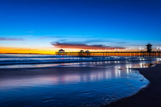 Huntington Beach Pier at Sunset Surreal scenery as the sun sets below the horizon along Huntington Beach, casting a beautiful glow and peaceful landscape. huntington beach california stock pictures, royalty-free photos & images