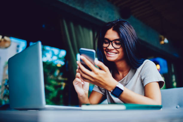 istock Cheerful female student happy getting SMS from boyfriend with doing homework in cafe interior, successful young entrepreneur excite with first business offer sending feedback to colleague on phone 898839408