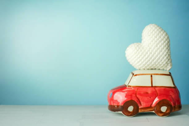 istock Miniature red car carrying a white heart on cyan background 898842704