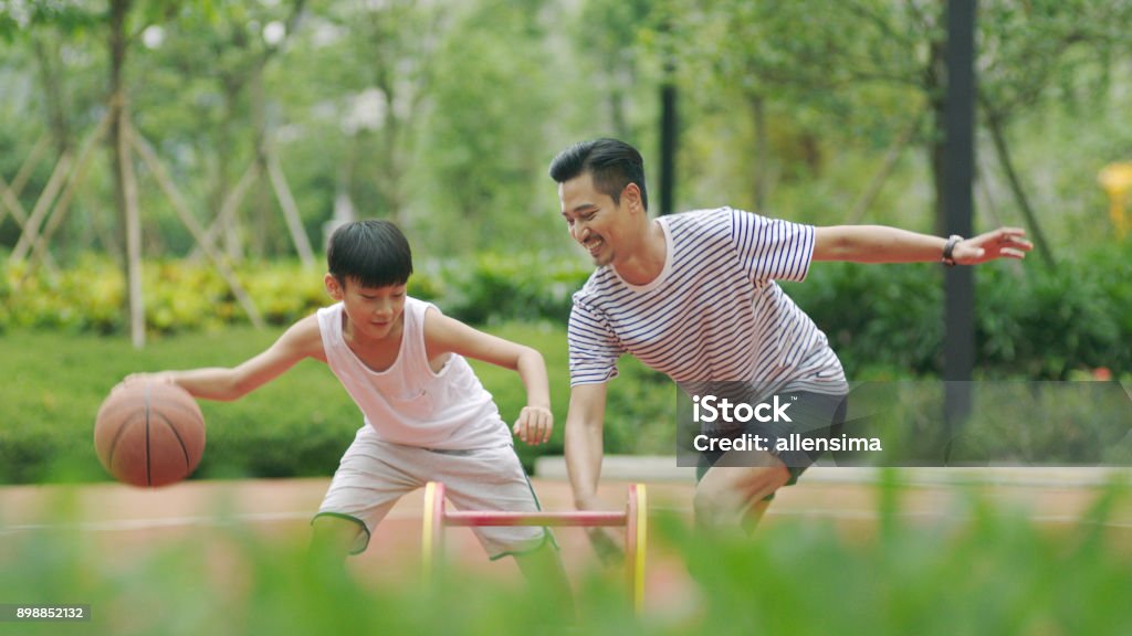 Asian father & son playing basketball in garden in morning Asian and Indian Ethnicities Stock Photo