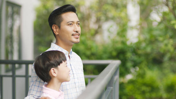 istock Asian father and his son standing on balcony enjoying fresh nature 898852186