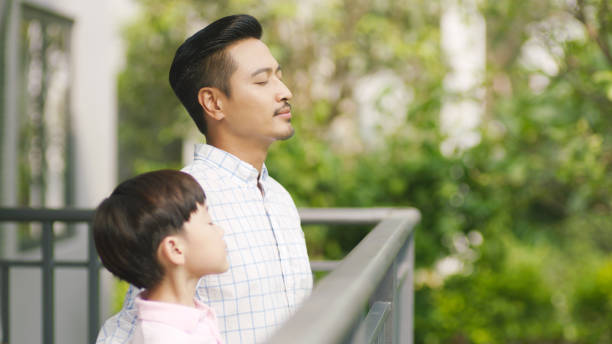 Asian father and his son standing on balcony enjoying fresh nature