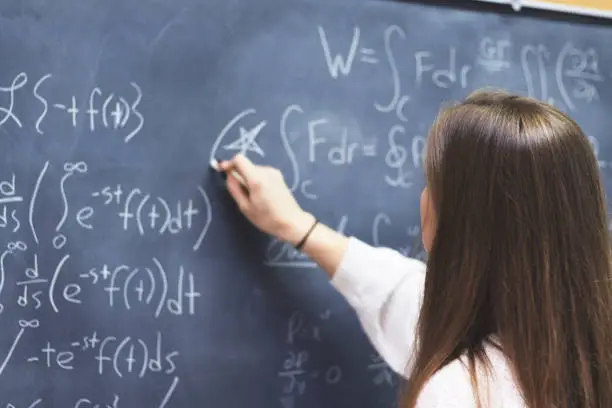 Female STEM student circling an important formula she wrote on the board.