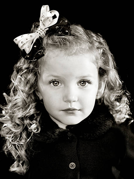 Little girl with curls and a bow stock photo