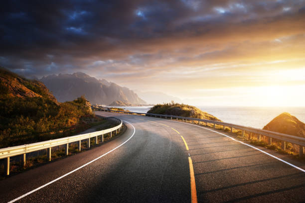 oad in mare all'alba, isola delle lofoten, norvegia - autumn road landscape mountain foto e immagini stock