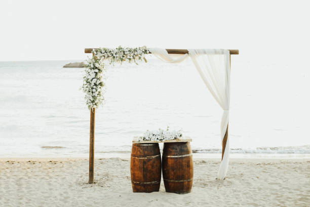 Two wedding rings in a heart lei on beach vacation. Hawaiian flower necklace lying on the sand in the shape of a heart with rings for marriage proposal in tropical vacation destination honeymoon.
