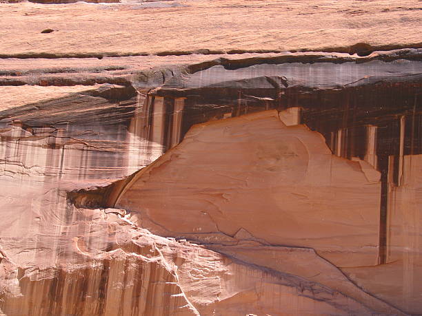 Canyon de Chelly National Monument, in northeastern Arizona, preserves nearly 5,000 years of human history within its dramatic sandstone walls. The canyon has been home to Ancestral Puebloans, known as the Anasazi, who built cliff dwellings here between 350 and 1300 CE, and to the Diné (Navajo) people who continue to live and farm within its sheltered valleys today. Carved by the forces of water and wind over millions of years, the canyon’s sheer cliffs rise to 1,000 feet above the canyon floor, revealing layers of ancient rock from the Permian period. From these rim overlooks, visitors can gaze down upon a living landscape where Navajo families maintain their traditions amidst towering formations, cottonwood groves, and sacred archaeological sites.  This scene was photographed at the Sliding House Overlook on the South Rim at Canyon de Chelly National Monument near Chinle, Arizona, USA.
