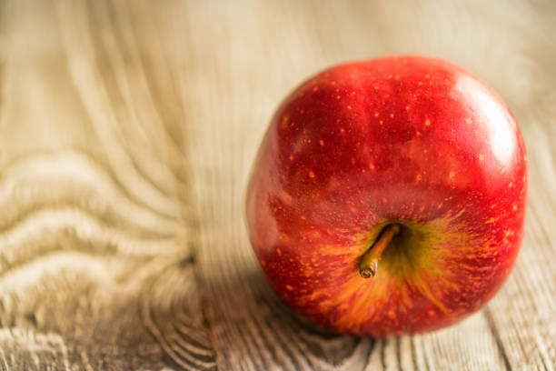 istock Red juice ripe apple on wooden background 898889574