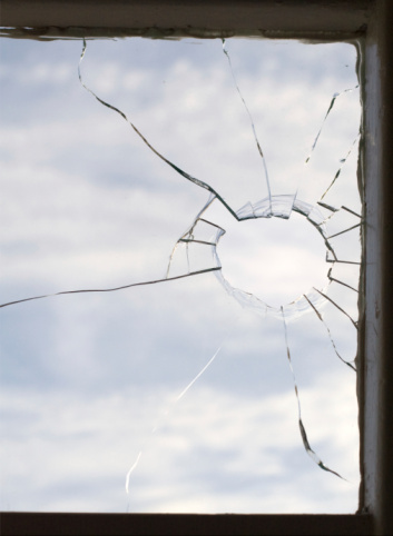 Broken glass on the window with sky with clouds in the background