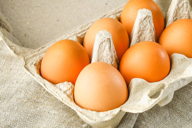istock Raw brown chicken eggs in a cardboard tray with cells on sacking on a white wooden table. Ingredients for cooking. 898898252
