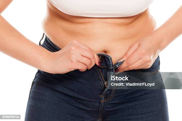 A Young Woman Has Difficulty Buttoning Her Jeans Stock Photo - Download Image Now - Women, Too Small, One Woman Only