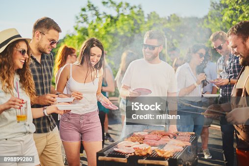 istock Group of people standing around grill. 898899280