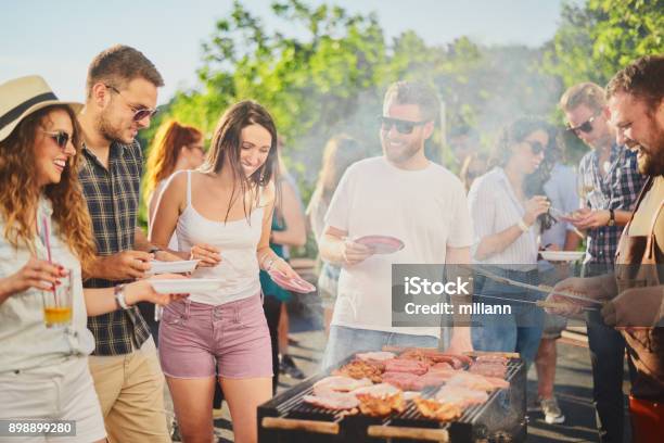 Group Of People Standing Around Grill Stock Photo - Download Image Now - Barbecue - Meal, Barbecue - Social Gathering, Barbecue Grill