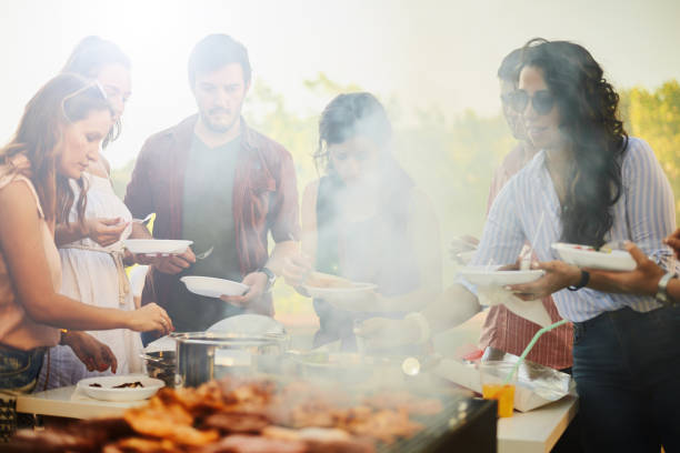 istock Group of people standing around grill. 898899302