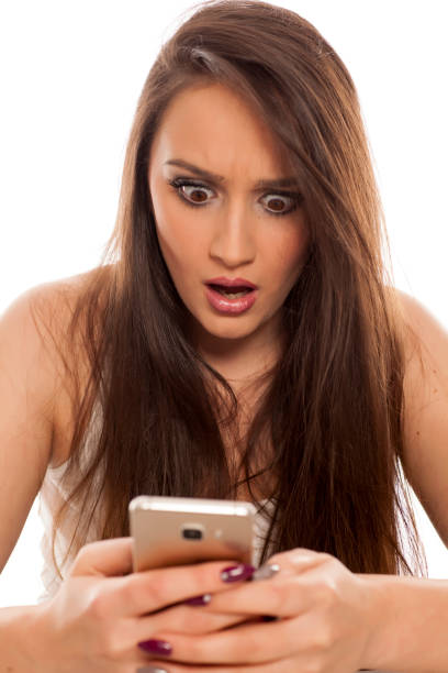 istock Shocked young woman looking in her smartphone on white background 898901806