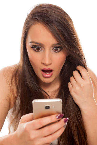 istock Shocked young woman looking in her smartphone on white background 898901808