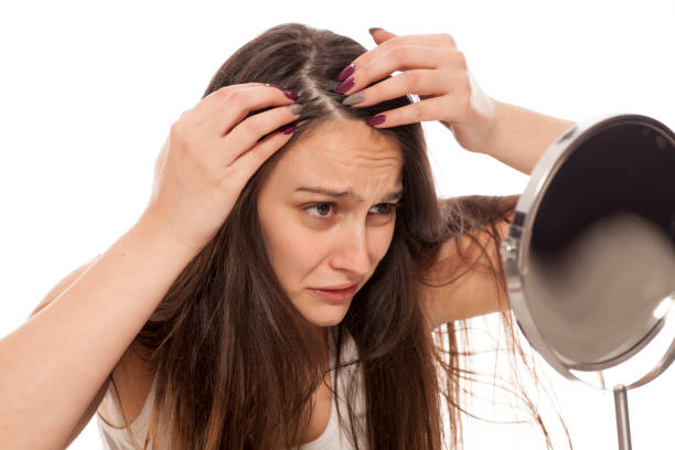 giovane donna nervosa guarda i capelli allo specchio - isolated on white brown white anxiety foto e immagini stock