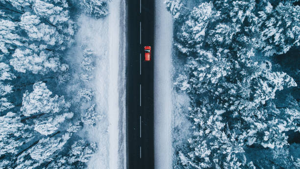 vista aérea del camino en invierno con el coche rojo en él - snow car winter road fotografías e imágenes de stock