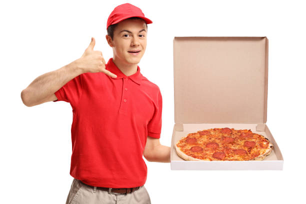 Teenage pizza delivery boy holding a pizza box and making a call me gesture Teenage pizza delivery boy holding a pizza box and making a call me gesture isolated on white background pizza delivery stock pictures, royalty-free photos & images