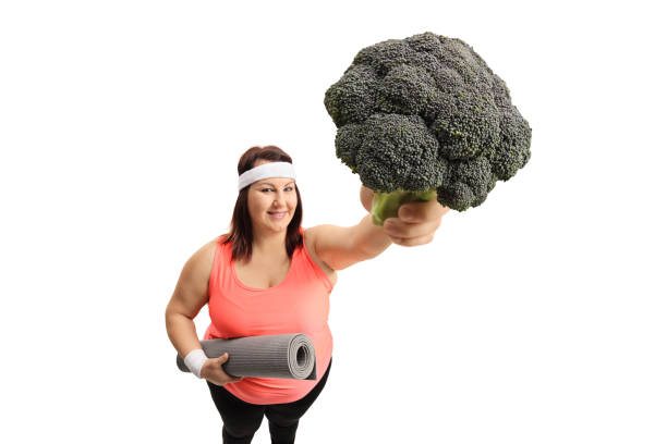 istock Overweight woman with an exercise mat and broccoli 898915854