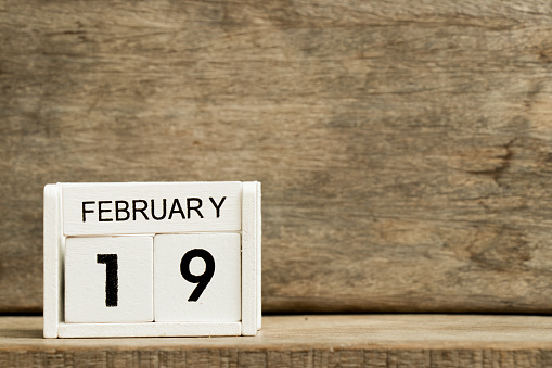 White block calendar present date 19 and month February on wood background