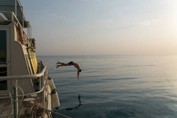 istock Man jump into the water from the yacht 898921028
