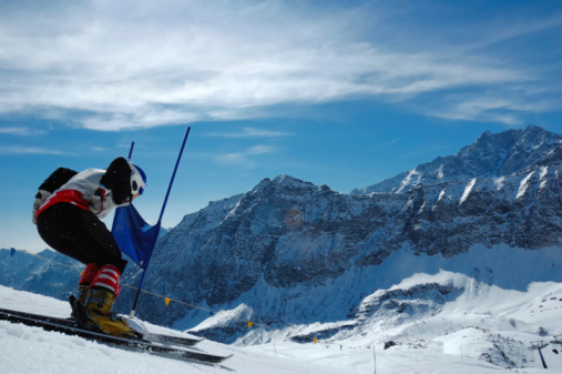 Young ski racer doing downhill slalom. Italian Alps, Europe.