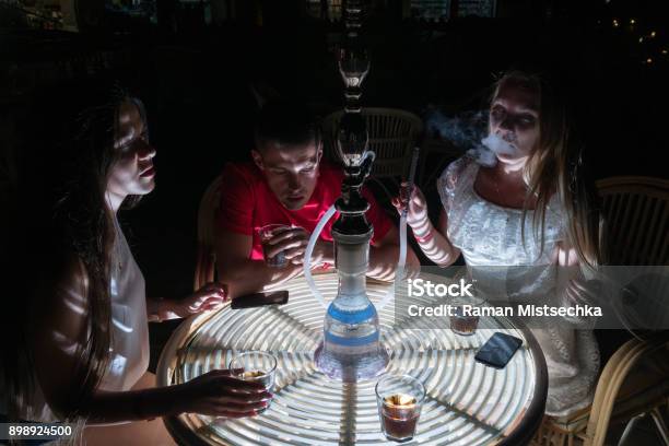 Friends Smoke Hookah And Drink Alcohol At A Night Cafe Stock Photo - Download Image Now