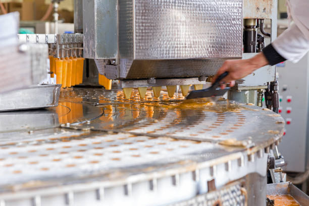 Close-up of an employee preparing guava sweets at a stainless steel table, with sweets arranged beside her