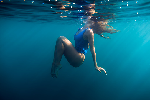 Underwater woman portrait in blue ocean with day light.