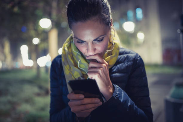 istock Single. Pretty young woman, using mobile phone, outdoors. She is sitting in the park bench. Defocused city lights in background. Shallow DOF 898938090