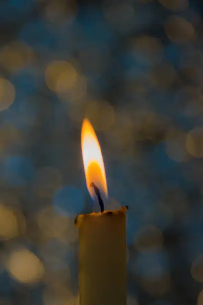 Photo of a candle burns, yellow, blue bokeh
