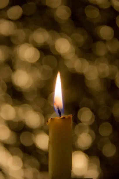 Photo of a candle burns, yellow, blue bokeh