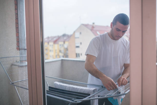 istock Man hanging clothes on a rack dryer 898946322