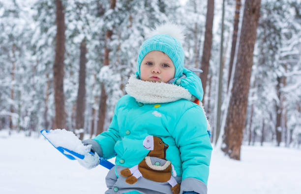 istock A child is playing in a winter park, scooping snow with a shovel 898946880