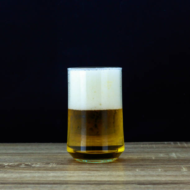 istock Glass beer on wooden table with black background 898947444
