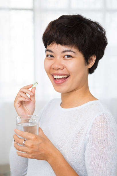 istock Cheerful Asian woman taking vitamin supplement 898950384