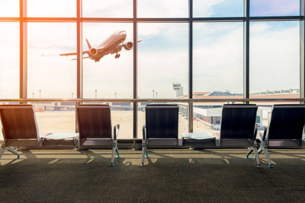 istock Airport terminal interior with empty seats, background a flying by airplane. 898951320