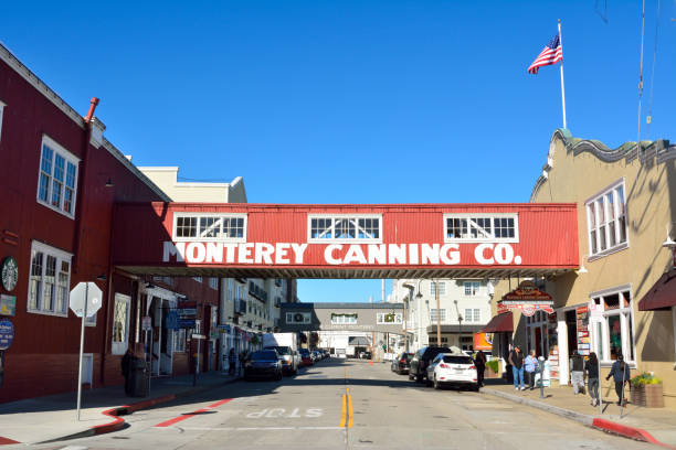 Street view in the Cannery Row district of Monterey, CA Monterey, California, United States of America - November 29, 2017. Street view in the Cannery Row district of Monterey, with historic buildings, wooden skywalk, cars and people. city of monterey california stock pictures, royalty-free photos & images