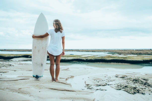 istock Woman Standing on Sand Beach With Surfboard 898958918