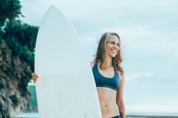 istock Smiling Woman Standing With Surfboard on Beach 898958920