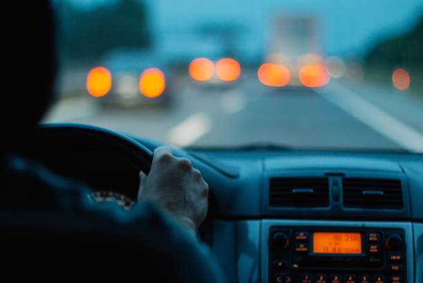 manos en el volante hombre conduciendo un coche por la noche - parabrisas fotos fotografías e imágenes de stock