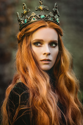 Red-haired woman in a green medieval dress near the castle