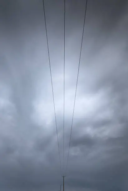 Electricity transmission lines  transferring electrical energy on a stormy cloudy sky