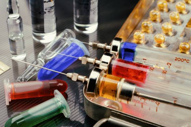 istock Syringes with medication on sterilization box, ampoules and vials with fluid on glossy surface. Toned 898968430